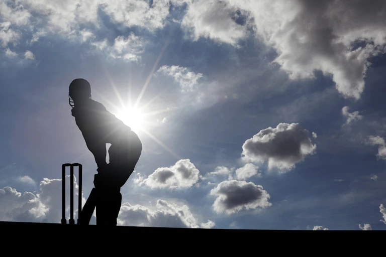Cricketer silhouetted against sun