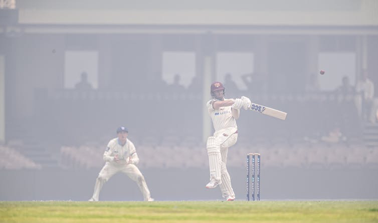 cricket players playing as bushfire smoke fills the ground