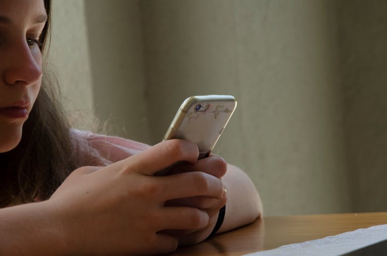 A close-up image of a girl looking at a smartphone.