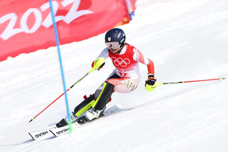Women's Slalom during the Beijing 2022 Olympic Winter Games, skiing down a hill with a red sign behind them.