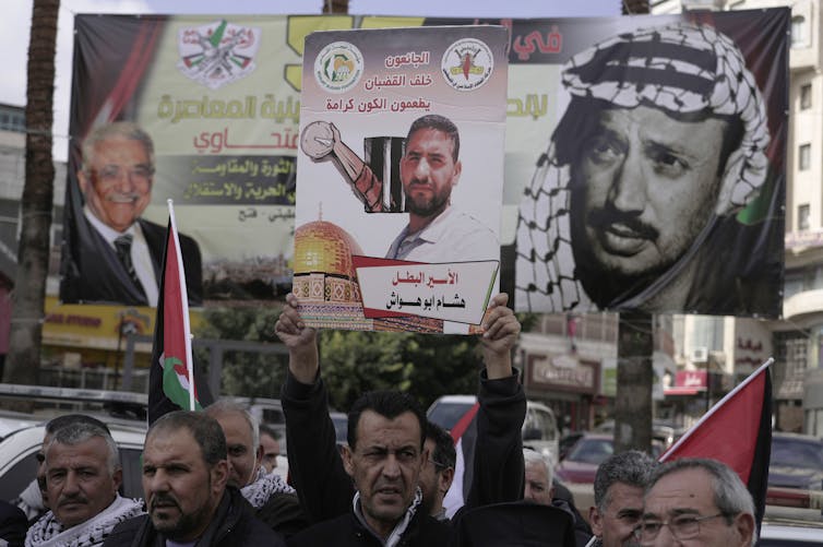 Protesters hold up signs with photos and messages written in Arabic