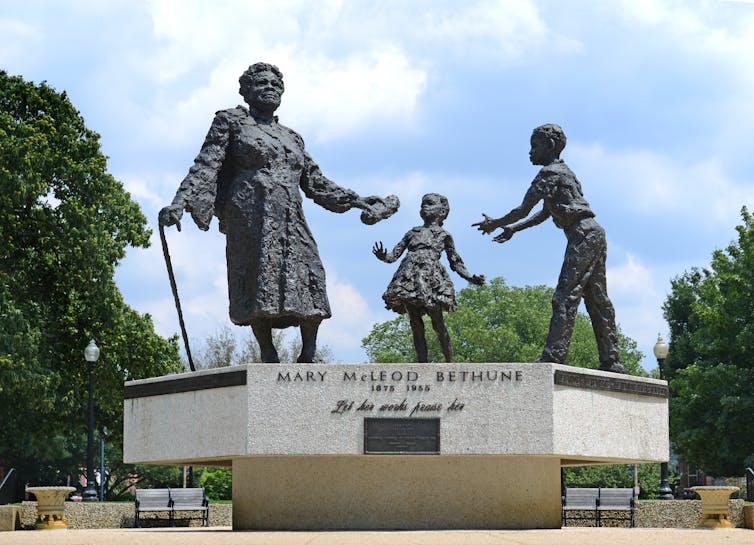 A statue of a Black woman giving a loaf of bread to two children.