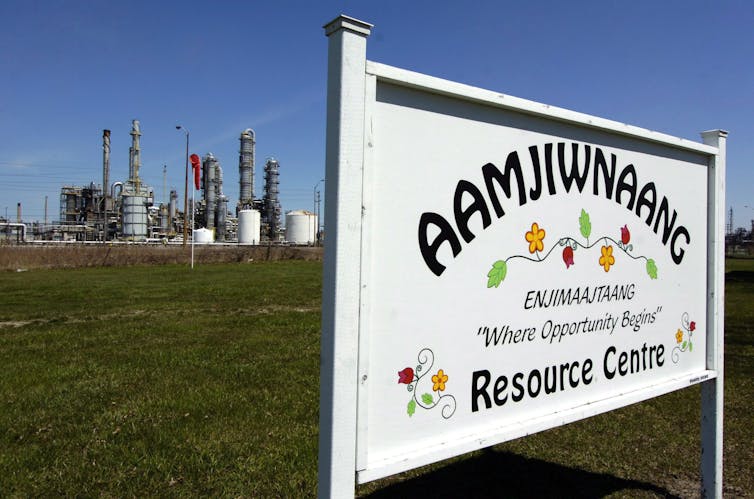 A sign for the Aamjiwnaang First Nation Resource Centre is seen in front of a chemical plant.