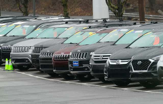 Used mostly black cars are lined up in a dealer parking lot.
