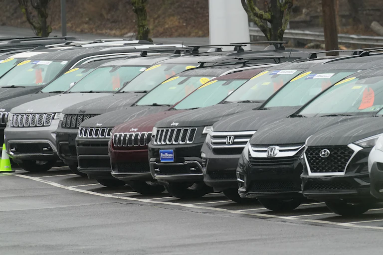 Used mostly black cars are lined up in a dealer parking lot.
