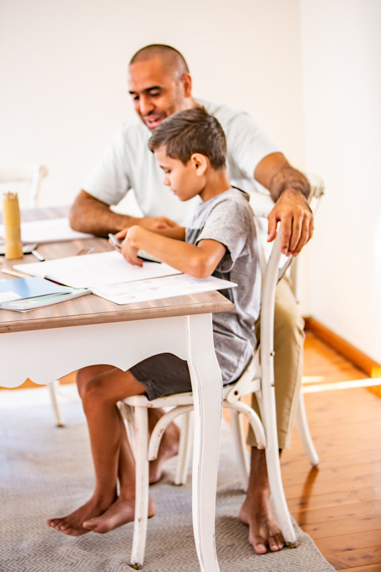 A young child does homework with their parent.