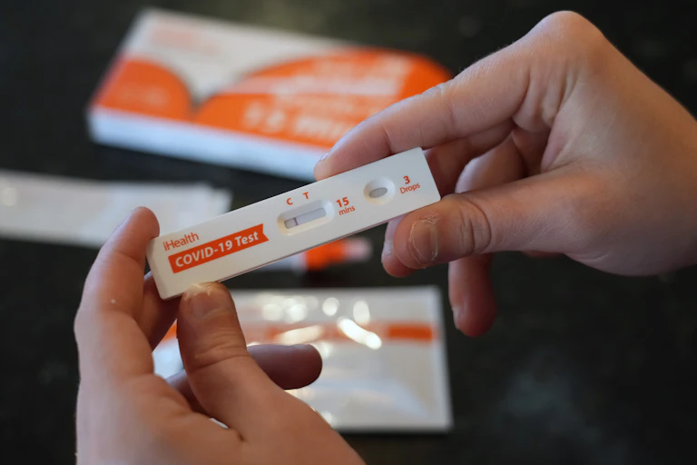 A hand holding a home COVID test kit.