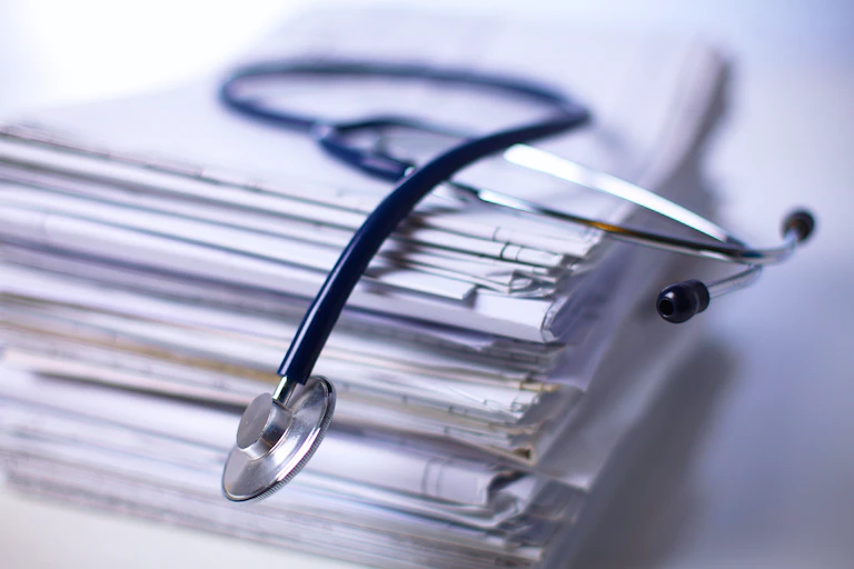 A stack of scientific studies, with a stethoscope laying on top of the pile.