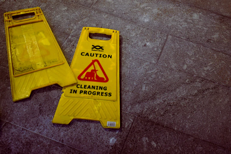 two caution hospital cleaning signs folded flat on the ground