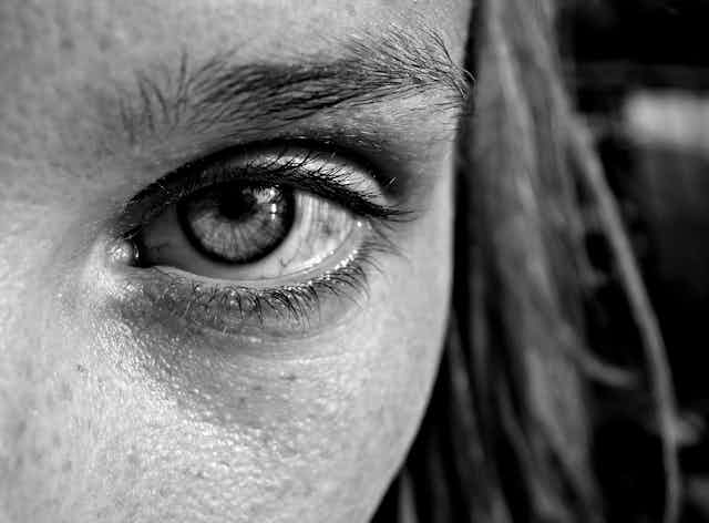 Black and white close up of a young woman's eye looking into the camera
