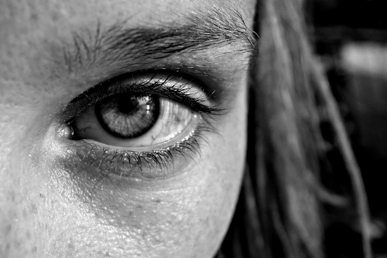 Black and white close up of a young woman's eye looking into the camera