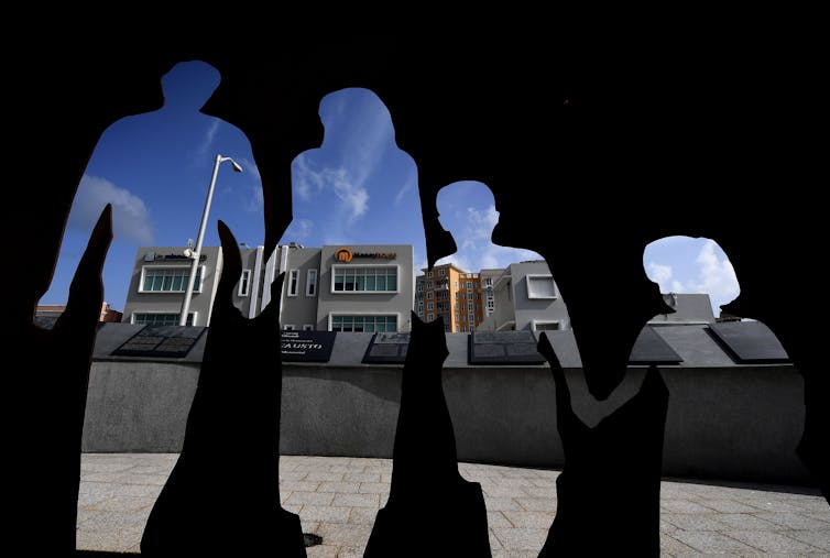 A silhouette of two adults and two children shows the outline of buildings in the background.