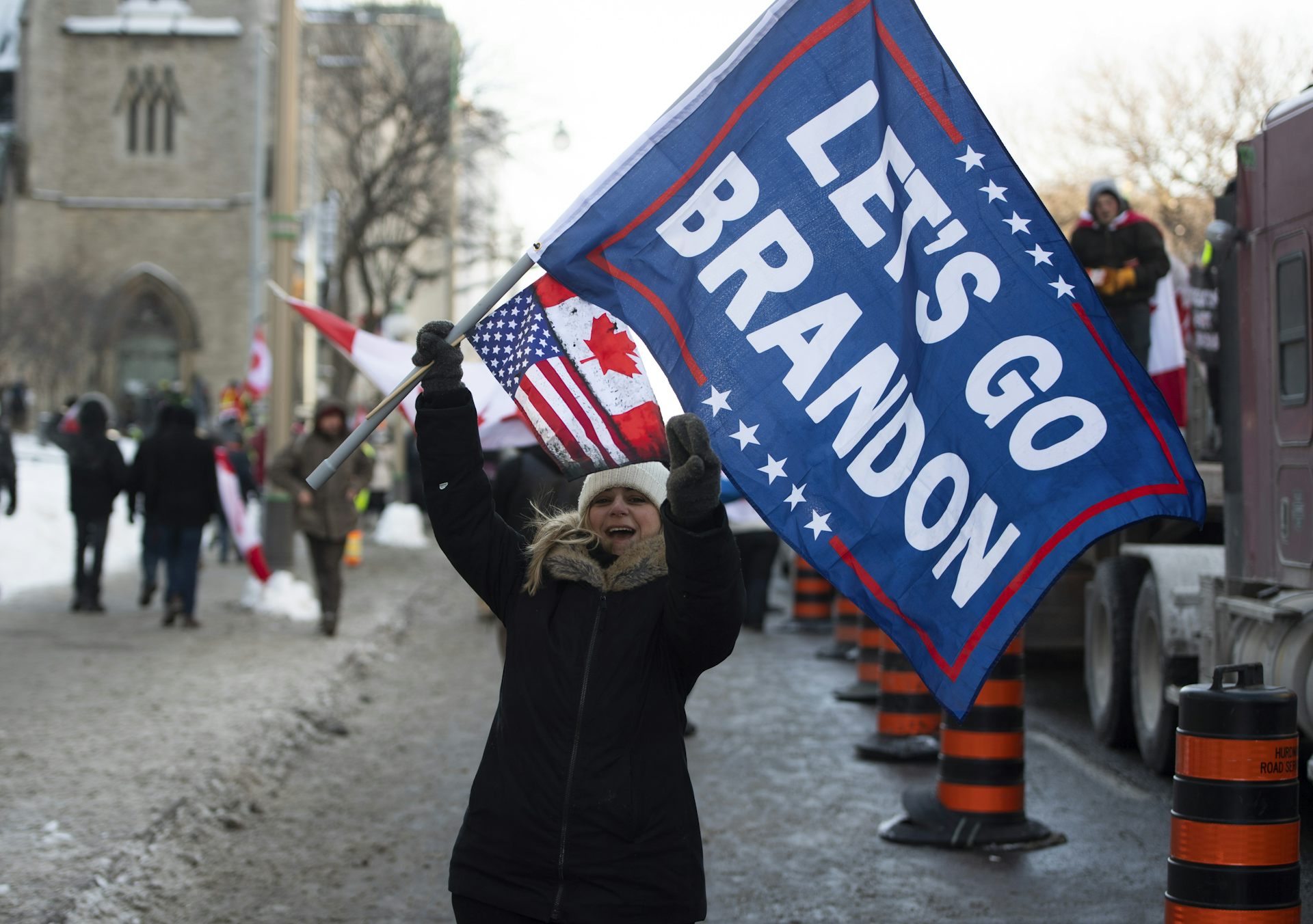 A smiling woman waves a 'Let’s Go Brandon' flag.