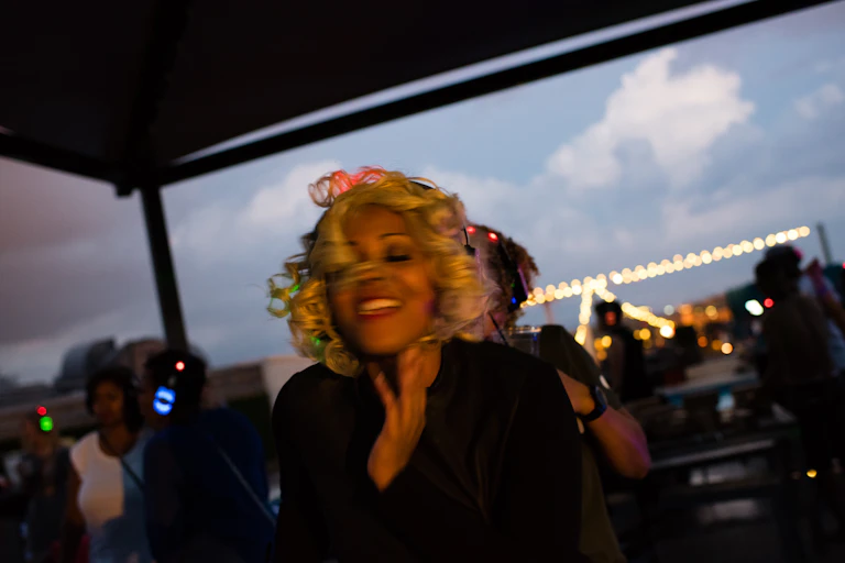 A woman smiles and dances to music she hears on her headphones