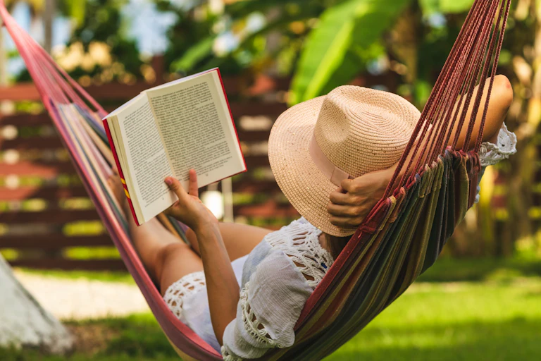 Woman in a hammock reading a book.