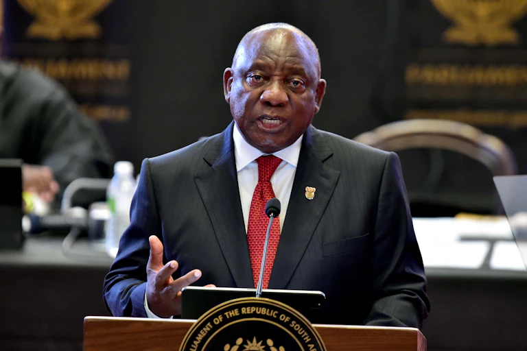 A man wearing a suit and tie delivers a speech at a podium.
