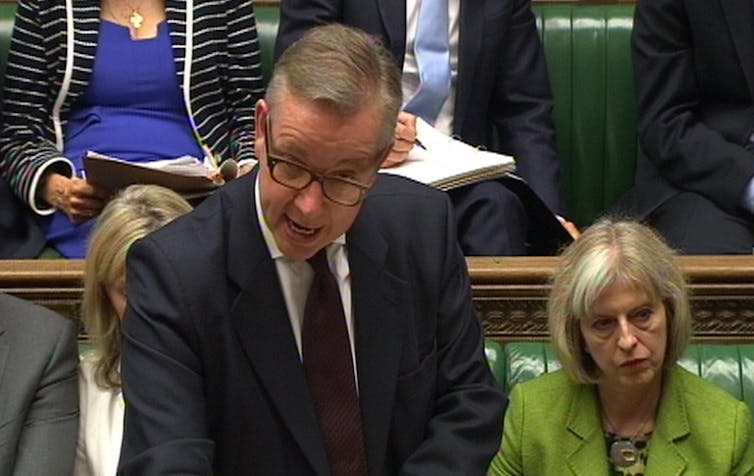 Michael Gove speaking at the dispatch box in the House of Commons with Theresa May sitting behind him.