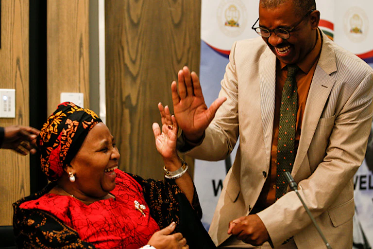 A woman and a man laugh while touching hands