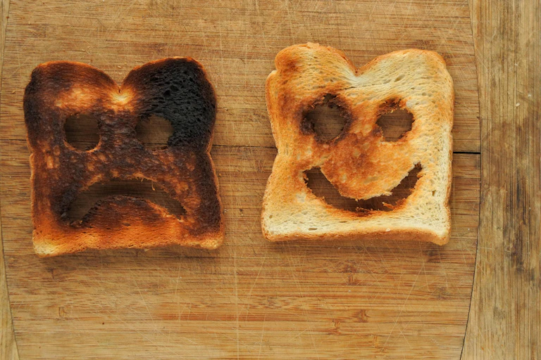 Burnt toast with a sad face and golden-brown toast with a smiley face