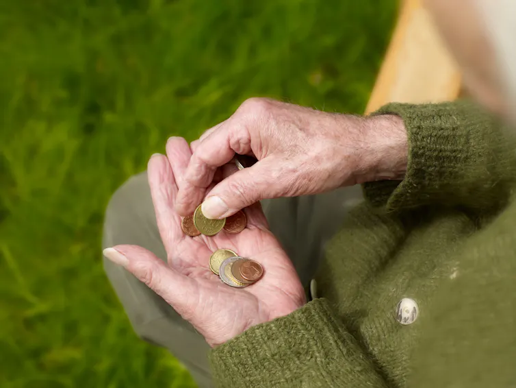 Elderly person's hands holding coins.