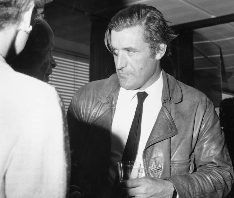 Man in jacket and tie holding drink.
