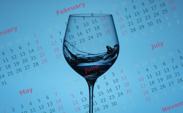 Wine glass against a calendar on a blue background