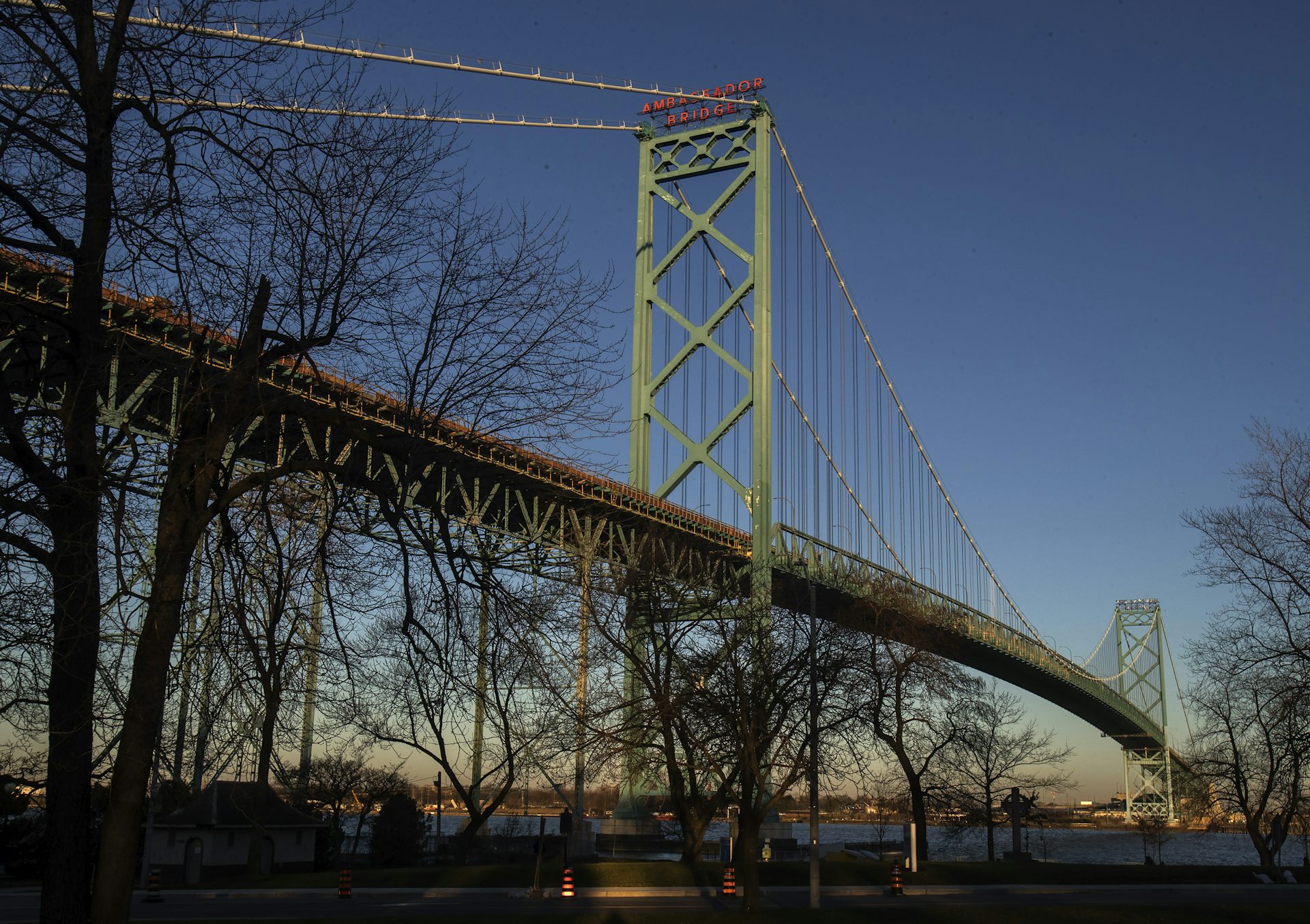 A bridge is shown at dusk with trees in the foreground.