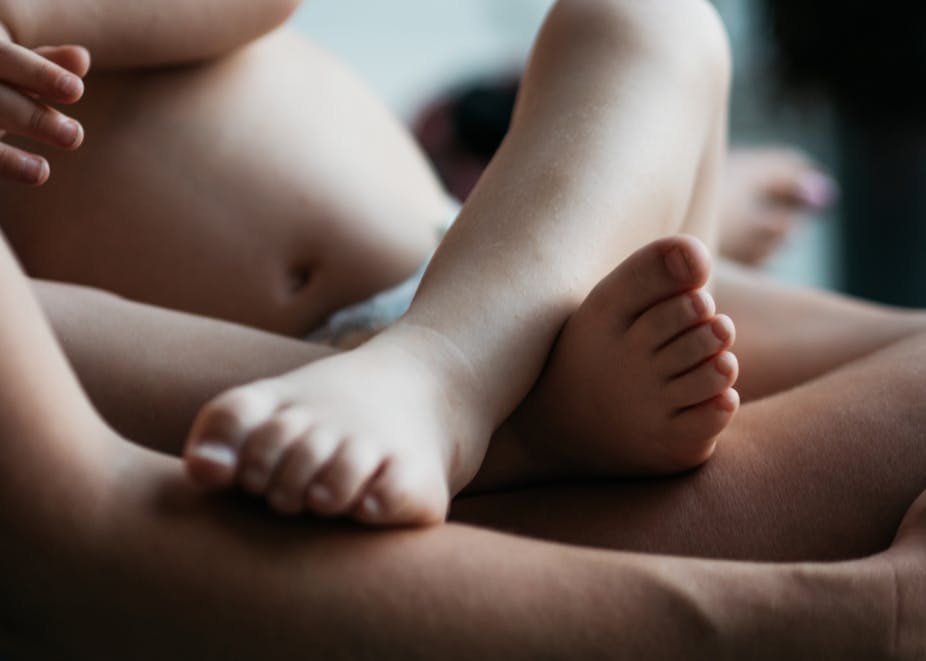 Close-up of infant's legs on parent's lap