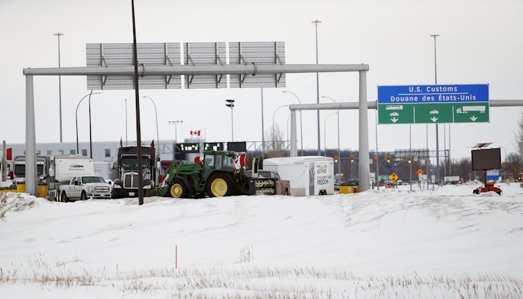 Trucks and tractors block a snowy highway.