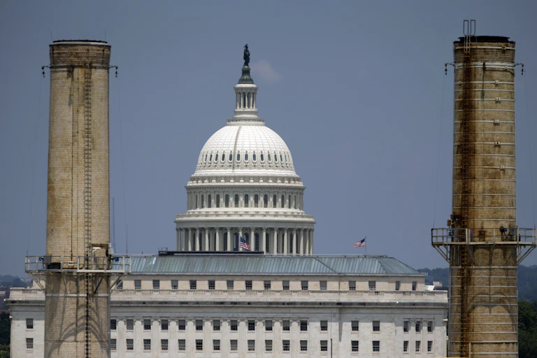 The U.S. Capitol seen through two power plant stacks.