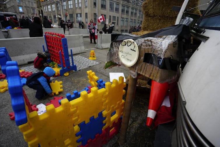 Children play in a makeshift play area with coloured blocks and toys.