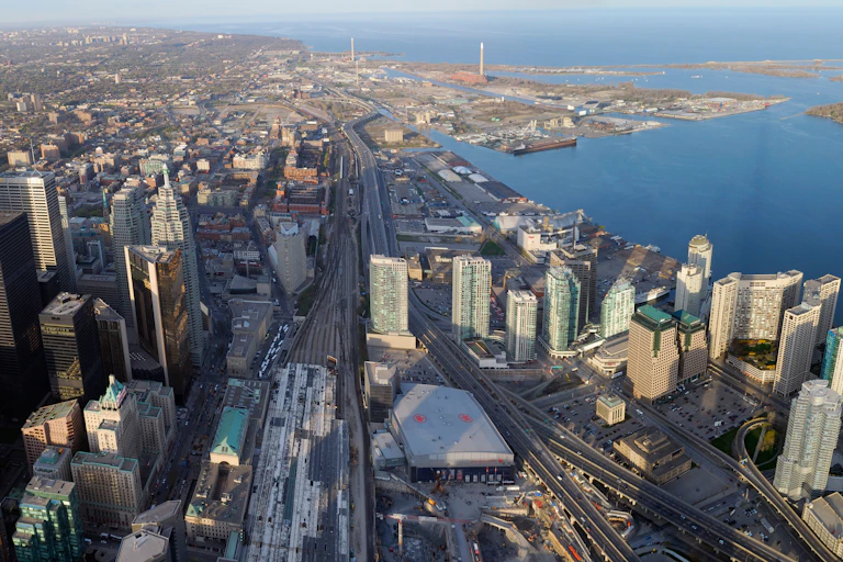Buildings and highways seen in an aerial view near a lake.
