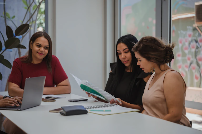 Three people sit in an office having a meeting.