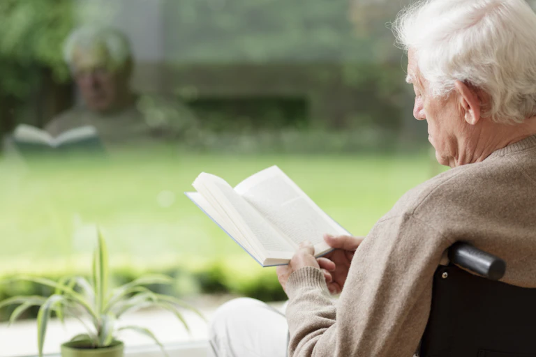 A older man reads a book in the sun.