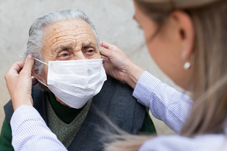 A nurse puts a mask on an elderly person.