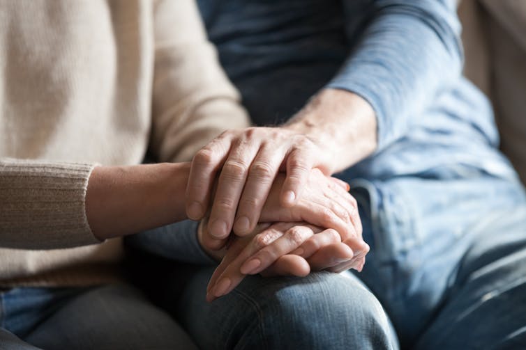 Carer holds the hand of an elderly relative.