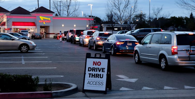 A queue of cars with a sign reading 'No drive thru access'