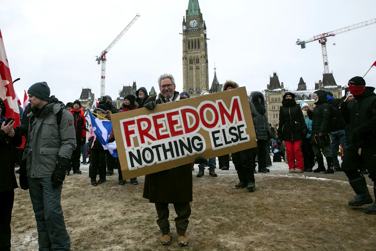 A man holds a sign on parliament hill that reads 'freedom nothing else'