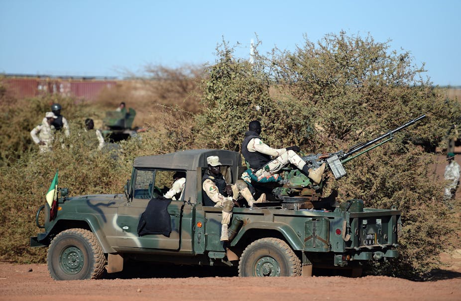 Men in military uniform seating on gun mounted vehicle.