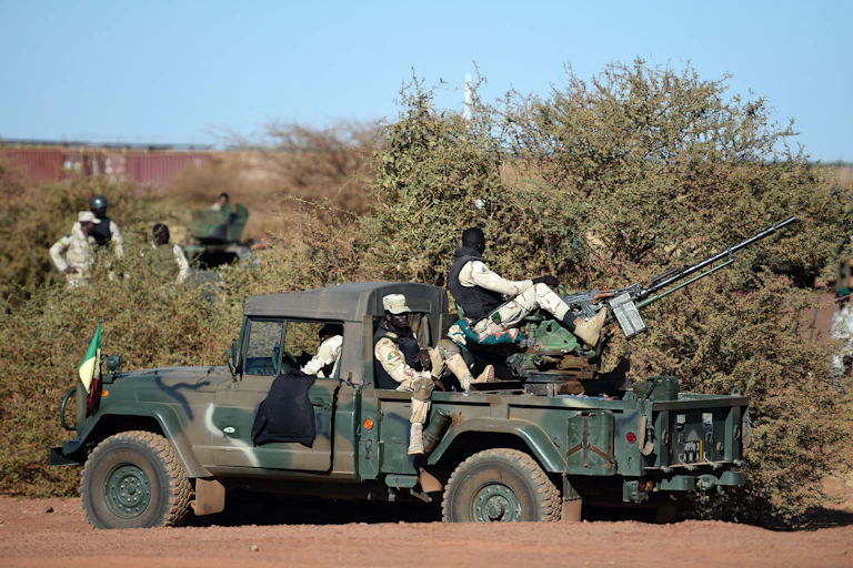 Men in military uniform seating on gun mounted vehicle.