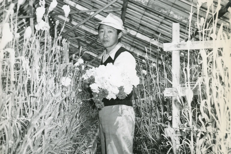 Man in hat holds bunch of flowers.