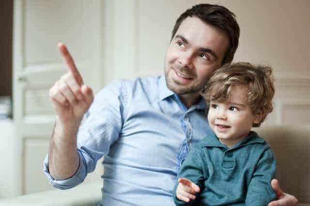 man holds toddler and both point