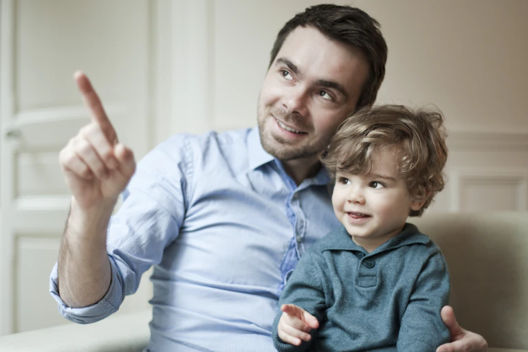 man holds toddler and both point