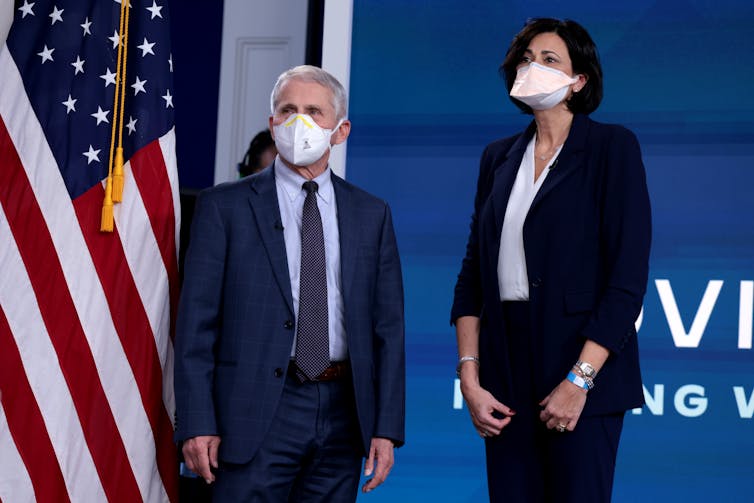 masked man and woman stand with American flag