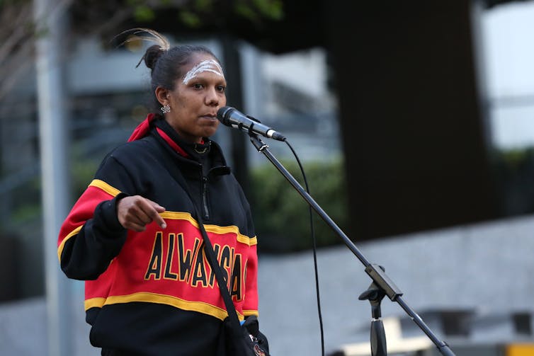 Woman stands at microphone at Australian BLM rally