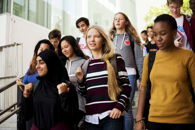 Diverse teenagers walking down school stairs
