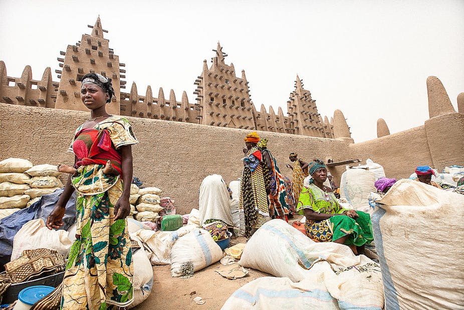 Sellers under the large mud mosque at Djenne market, Sahel, Mali.