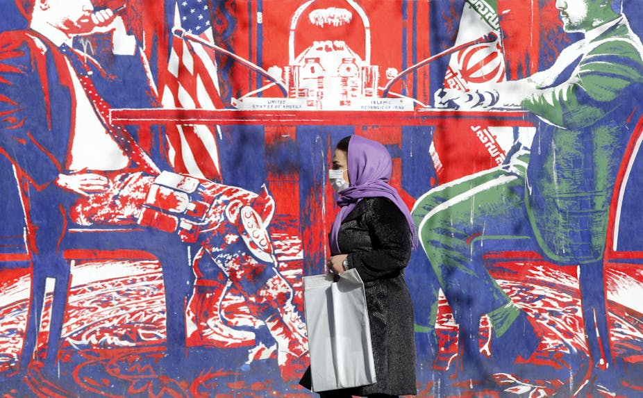 A woman walks past an anti-US mural on a wall in Tehran.