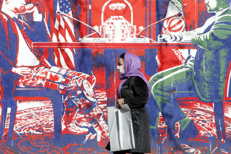 A woman walks past an anti-US mural on a wall in Tehran.
