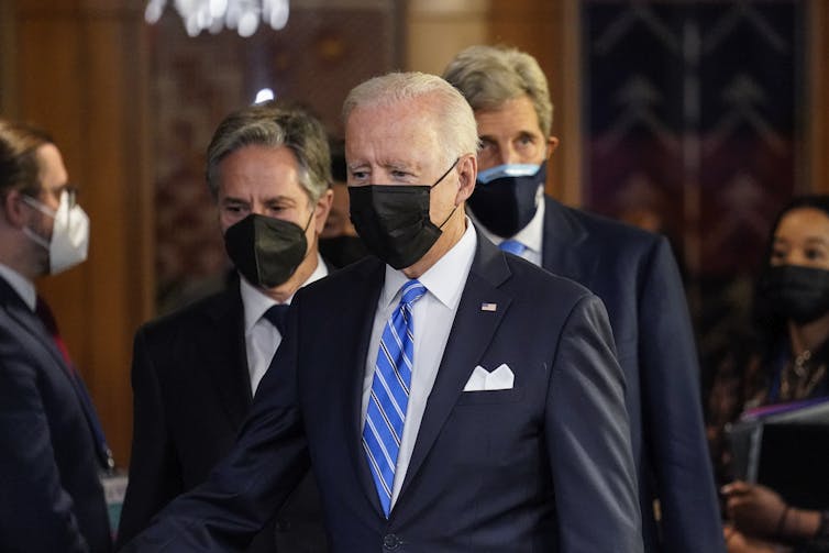 US president Joe Biden with secretary of state Antony Blinken and presidential environment envoy John Kerry, all wearing COVID masks